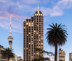 A high-rise building with multiple floors and balconies, surrounded by palm trees and other buildings. - Avani Auckland Metropolis Residences (Auckland)