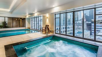 Una habitación de hotel con un ventanal grande, una piscina y un jacuzzi.