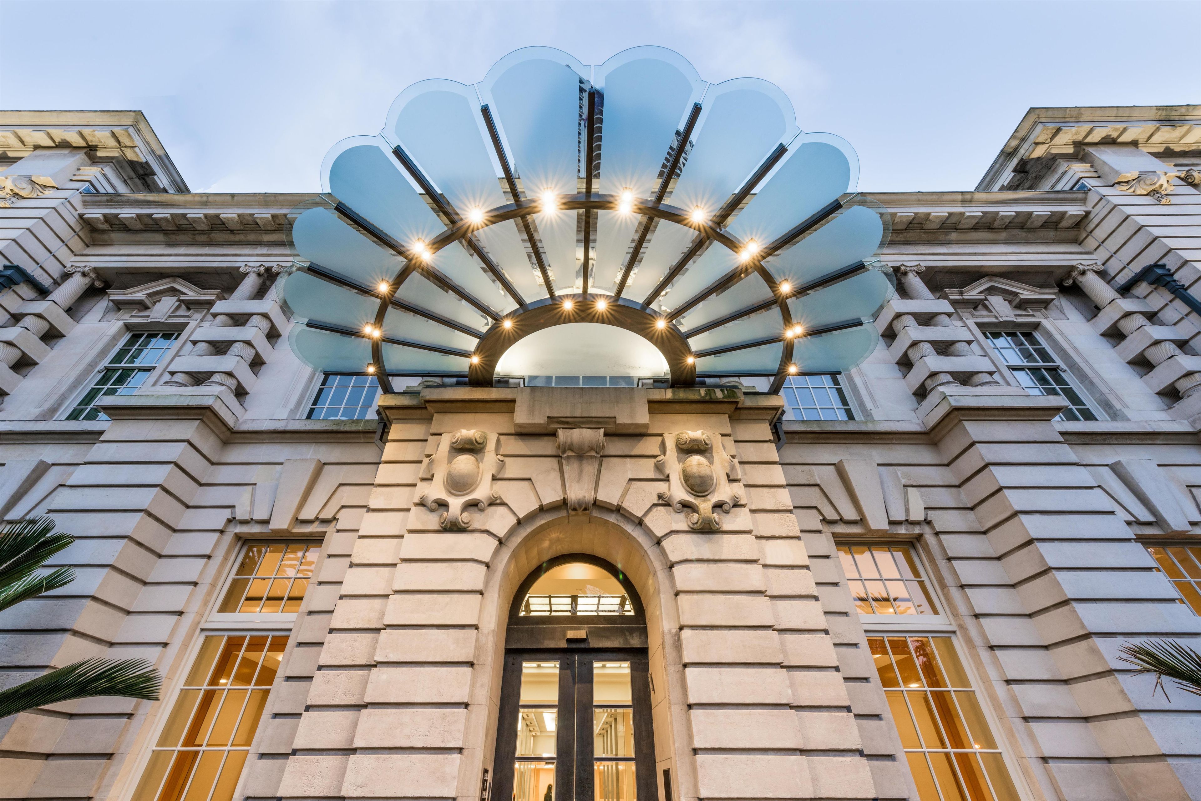A grand building with a large entrance, a decorative archway, and a prominent glass canopy structure above the entrance.