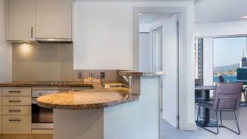 Una cocina moderna con encimeras de granito, electrodomésticos de acero inoxidable y vistas a la ciudad a través de amplios ventanales.