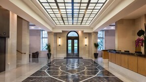 Eine geräumige Lobby mit einem geometrisch gemusterten Boden, einem Empfangstresen und einem großen Bogenportal.
