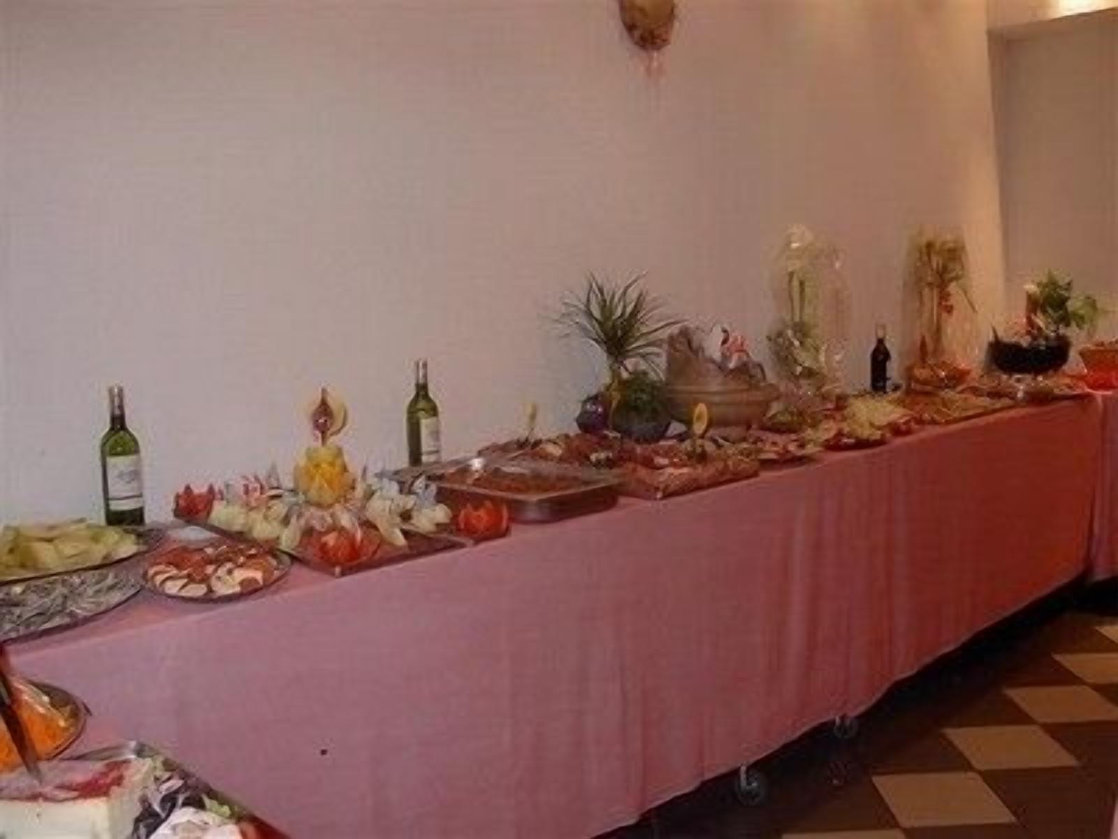 A buffet table with various food items, bottles of wine, and decorative plants.
