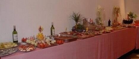 A buffet table with various food items, bottles of wine, and decorative plants.