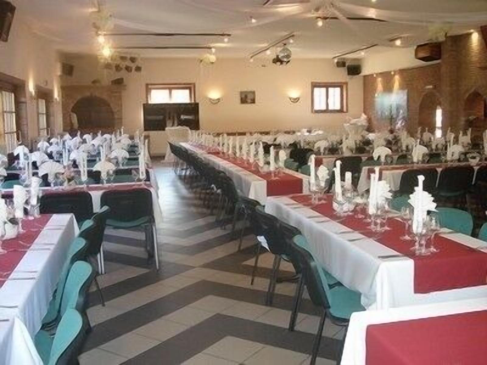 A long dining table with white tablecloths and teal chairs, set up for a formal event.