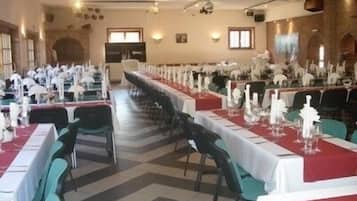 A long dining table with white tablecloths and teal chairs, set up for a formal event.