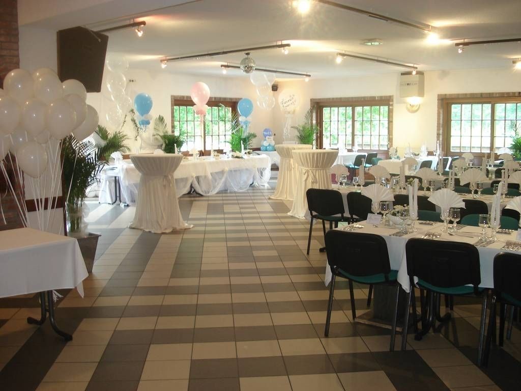 Un salón de banquetes con suelo a cuadros, mesas y sillas blancas.