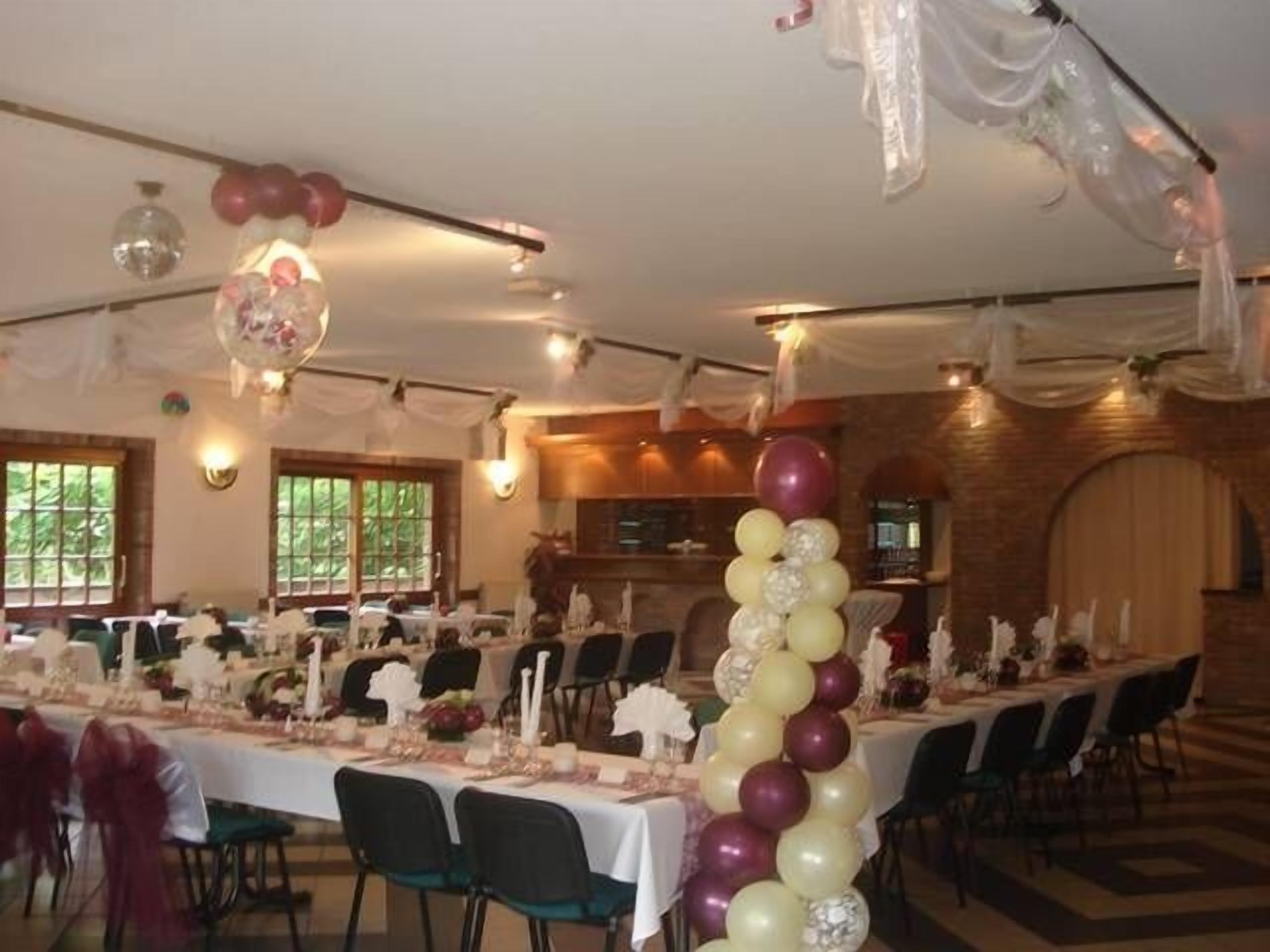 Un salón de banquetes con largas mesas dispuestas para comer, candelabros y una pared de ladrillo.