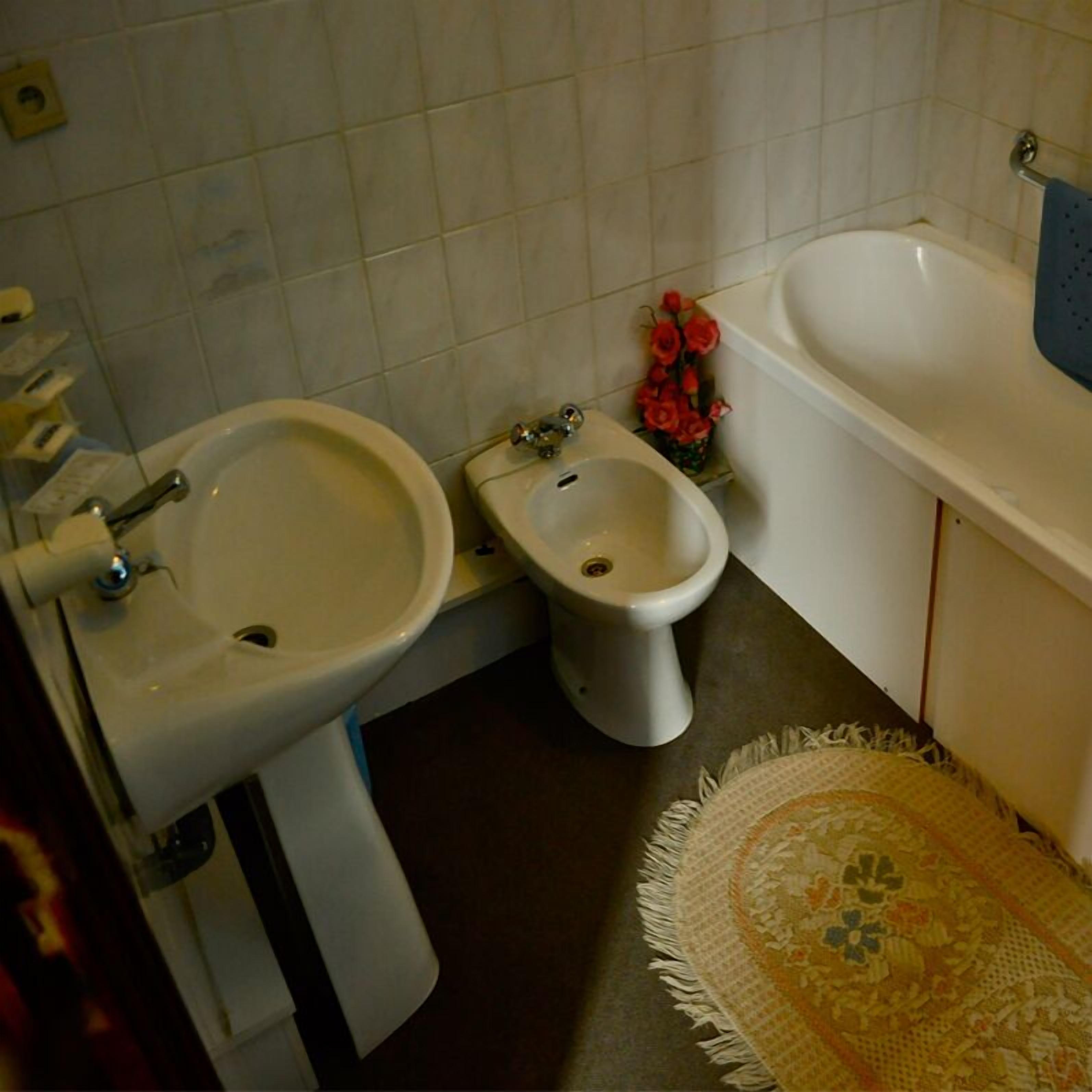 A bathroom with a bidet, a sink, and a bathtub.
