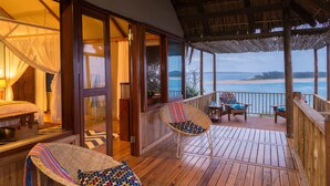 A wooden deck with wicker chairs and a view of the ocean.