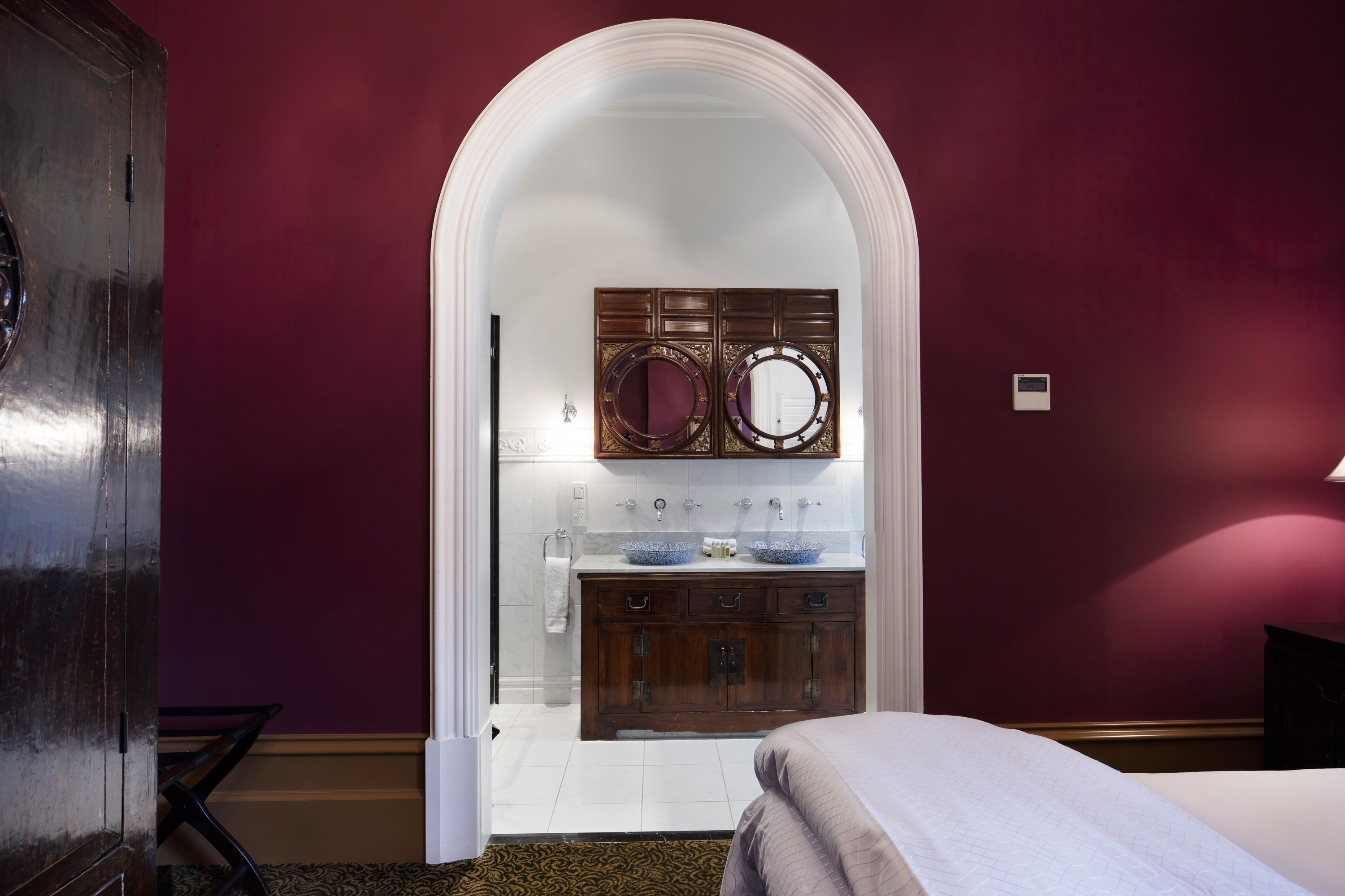A bedroom with a bed, a wooden dresser, and a vanity with a mirror.