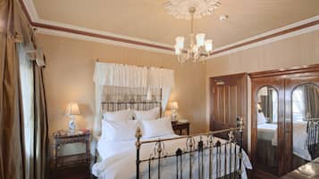 Een klassieke hotelkamer met een groot bed, een versierd plafond en een kroonluchter.