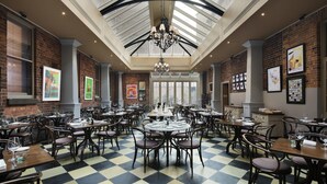 A spacious restaurant with high ceilings and skylights, featuring checkered flooring and multiple dining tables and chairs.