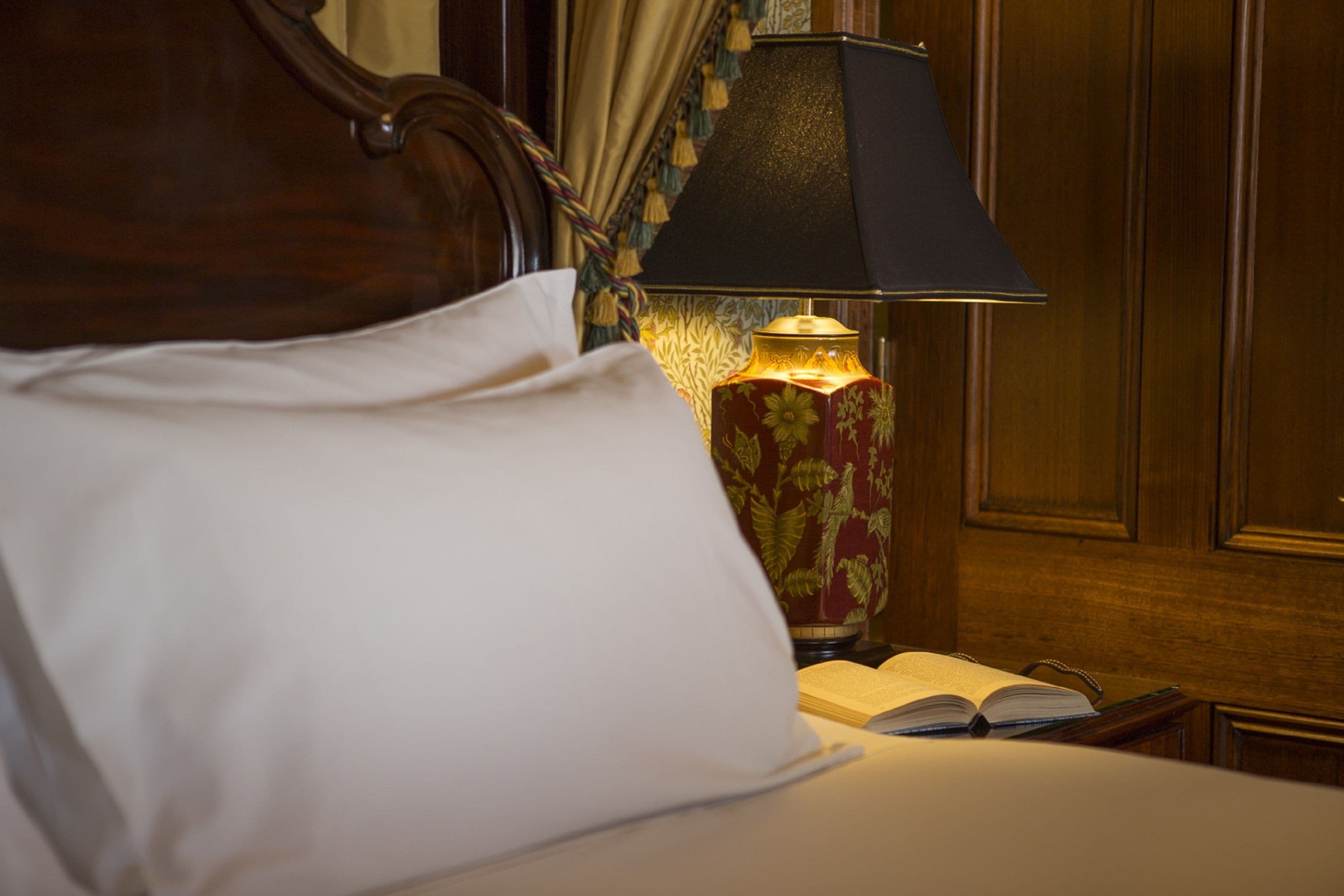 Una cama bien hecha con un almohadón blanco y un libro al lado.