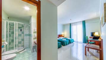 Une chambre d’hôtel avec douche, deux lits, un bureau et une télévision.