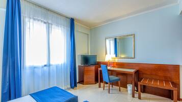 A hotel room with a bed, a desk, a chair, a TV, and a large mirror.