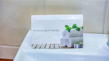 A bathroom with a white bathtub, a towel rack with rolled towels, and a small candle.