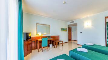 Una habitación de hotel con dos camas individuales, un escritorio con una computadora portátil, un televisor y un espejo.