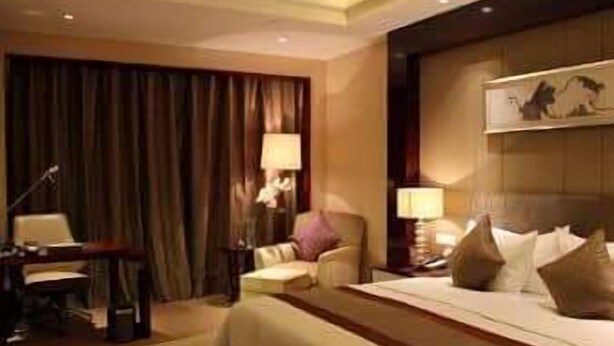 Ein Hotelzimmer mit einem großen Bett, einem Schreibtisch, einem Stuhl und einer Lampe.