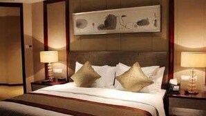 Ein Hotelzimmer mit einem großen Bett, zwei Nachttischen mit Lampen und einem Bild an der Wand.