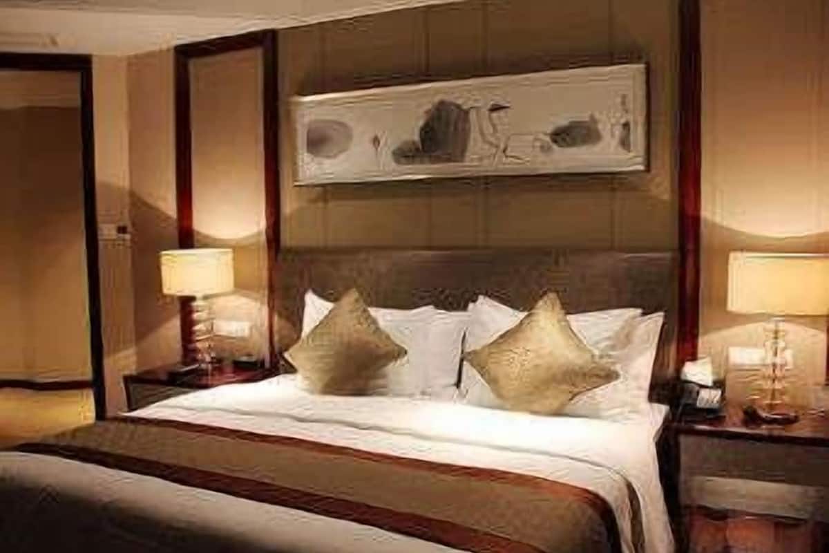 A hotel room with a large bed, two bedside tables with lamps, and a painting on the wall.