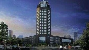 Ein modernes Hochhaus mit einer markanten Fassade, umgeben von Grünflächen und anderen Gebäuden.
