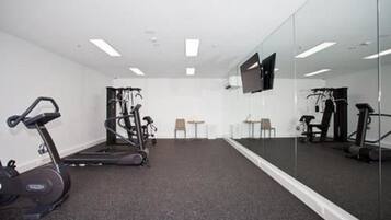 A gym with exercise equipment, a treadmill, and a mirrored wall.