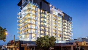 A multi-story hotel with balconies, a sign for 'Quest', and a 'Family Dental' clinic at the ground level. - Quest Mackay on Gordon (Mackay)