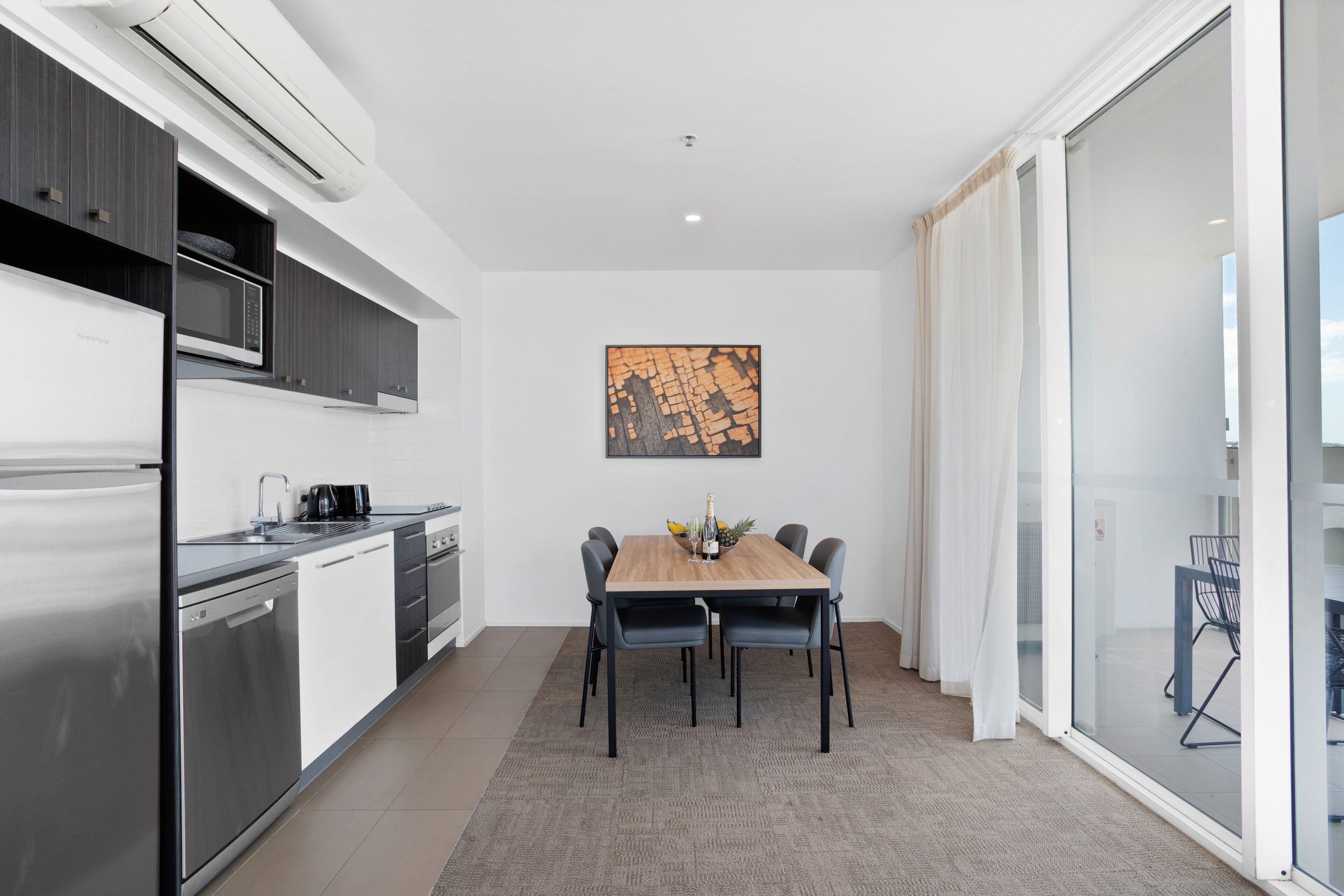 A modern kitchen with a built-in microwave, stainless steel appliances, and a dining area with a wooden table and chairs.