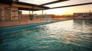 A swimming pool with a covered area and a sunset in the background. - Quest Mackay on Gordon (Mackay)