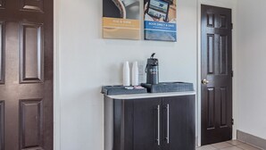 A reception area with a coffee machine, disposable cups, and a digital kiosk.