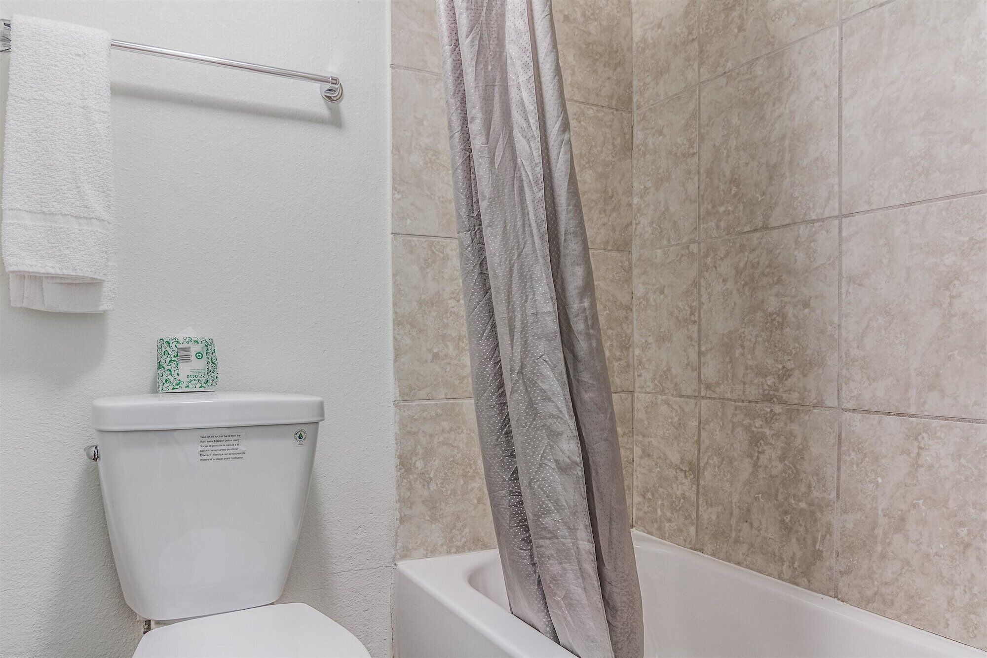 A bathroom with a toilet, a towel rack, and a shower curtain.