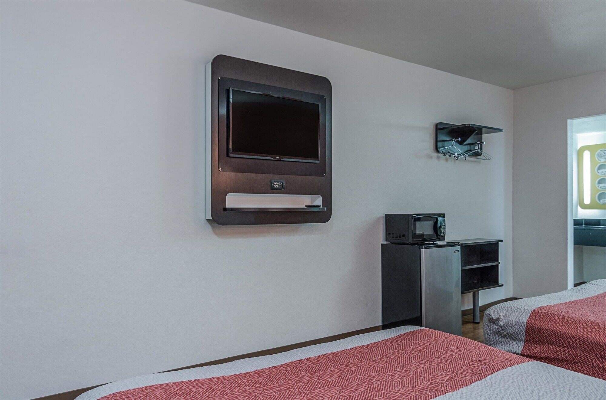 Une chambre d’hôtel équipée d’un téléviseur à écran plat fixé au mur, d’un four à micro-ondes posé sur une petite table et de deux lits avec une literie à motifs.