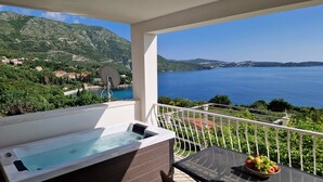 A balcony with a hot tub, a bowl of fruit, and a scenic view of a lake and mountains. - Arba Seaview Residences (Zupa dubrovacka)