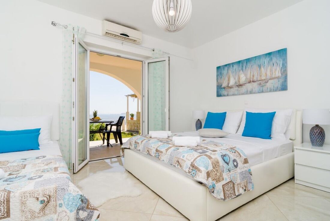 A bedroom with two beds, a painting, and a view of the outdoors.
