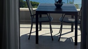 A balcony with a table and chairs, overlooking a calm sea and a distant island. - Arba Seaview Residences (Zupa dubrovacka)