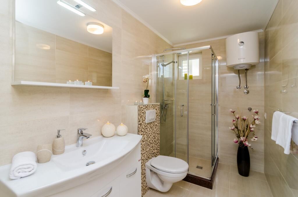 Een moderne badkamer met een douche met glazen wand, een groot wastafel en een toilet.