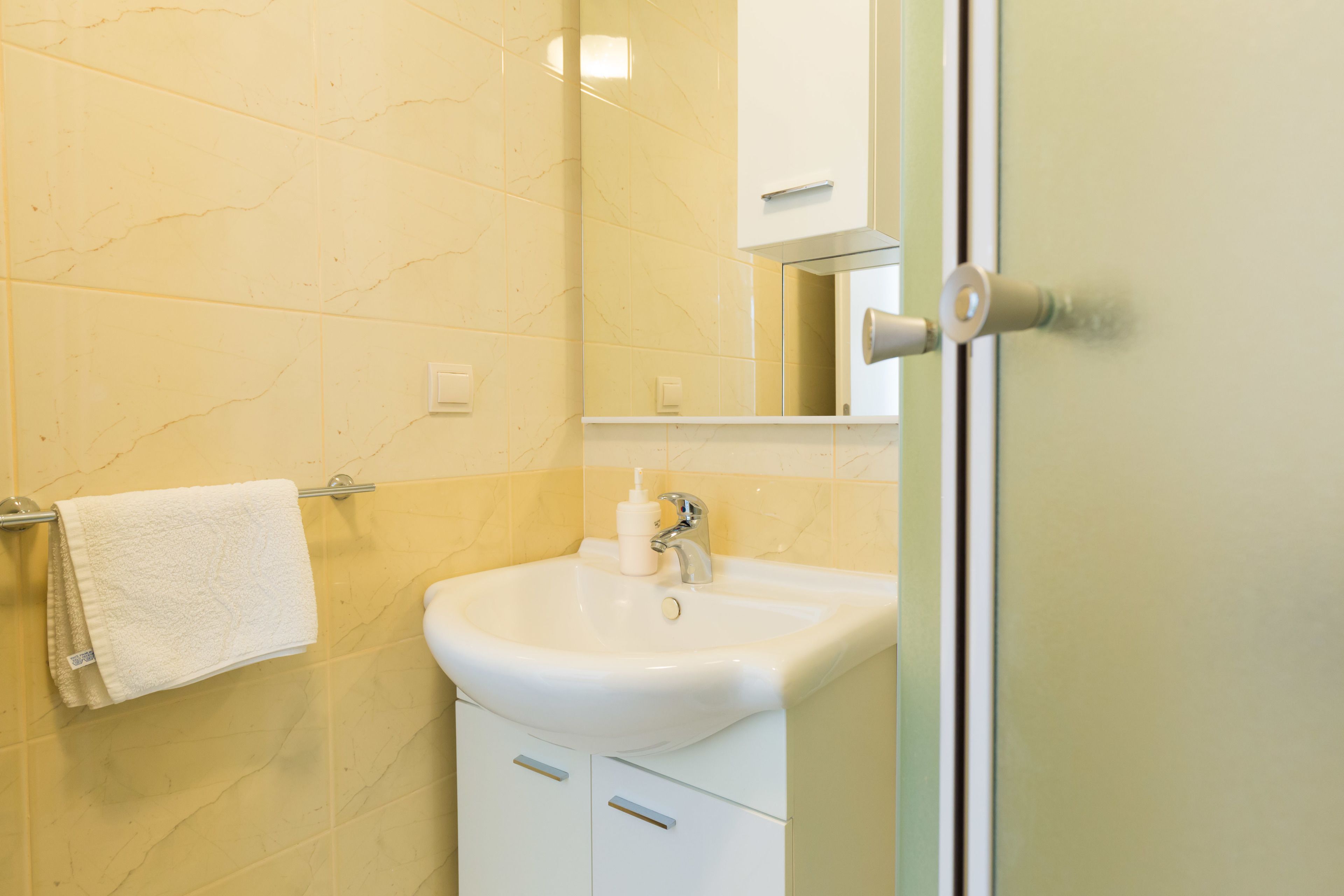 A bathroom with a white sink, a towel hanging on a rack, and a mirror above the sink.