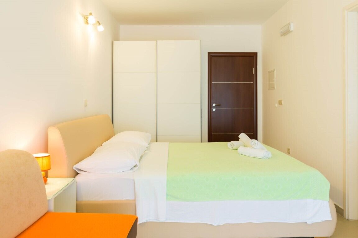 A hotel room with a bed, a nightstand with a lamp, a wardrobe, and a door.