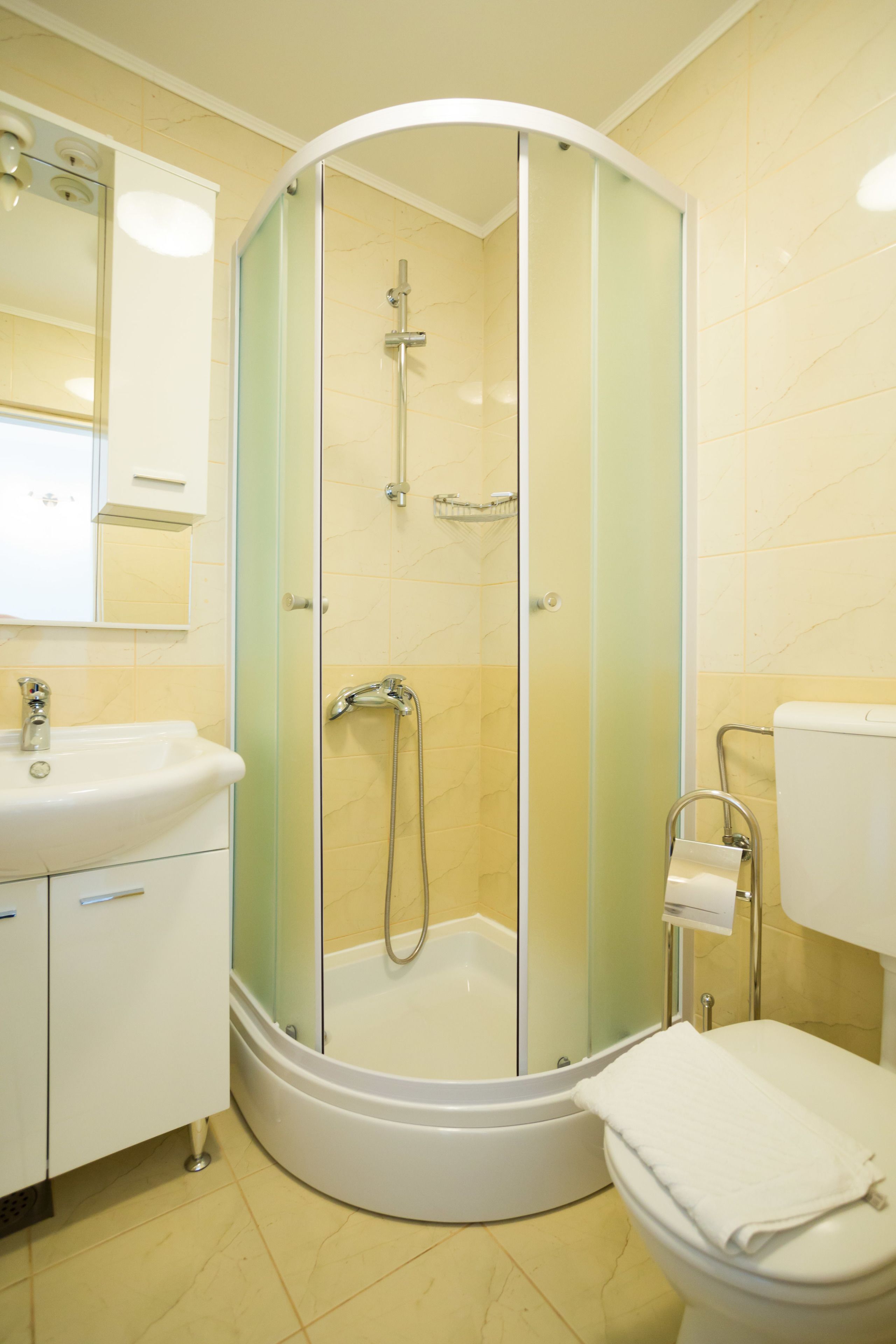 A modern bathroom with a glass-enclosed shower, a white sink, and a toilet.