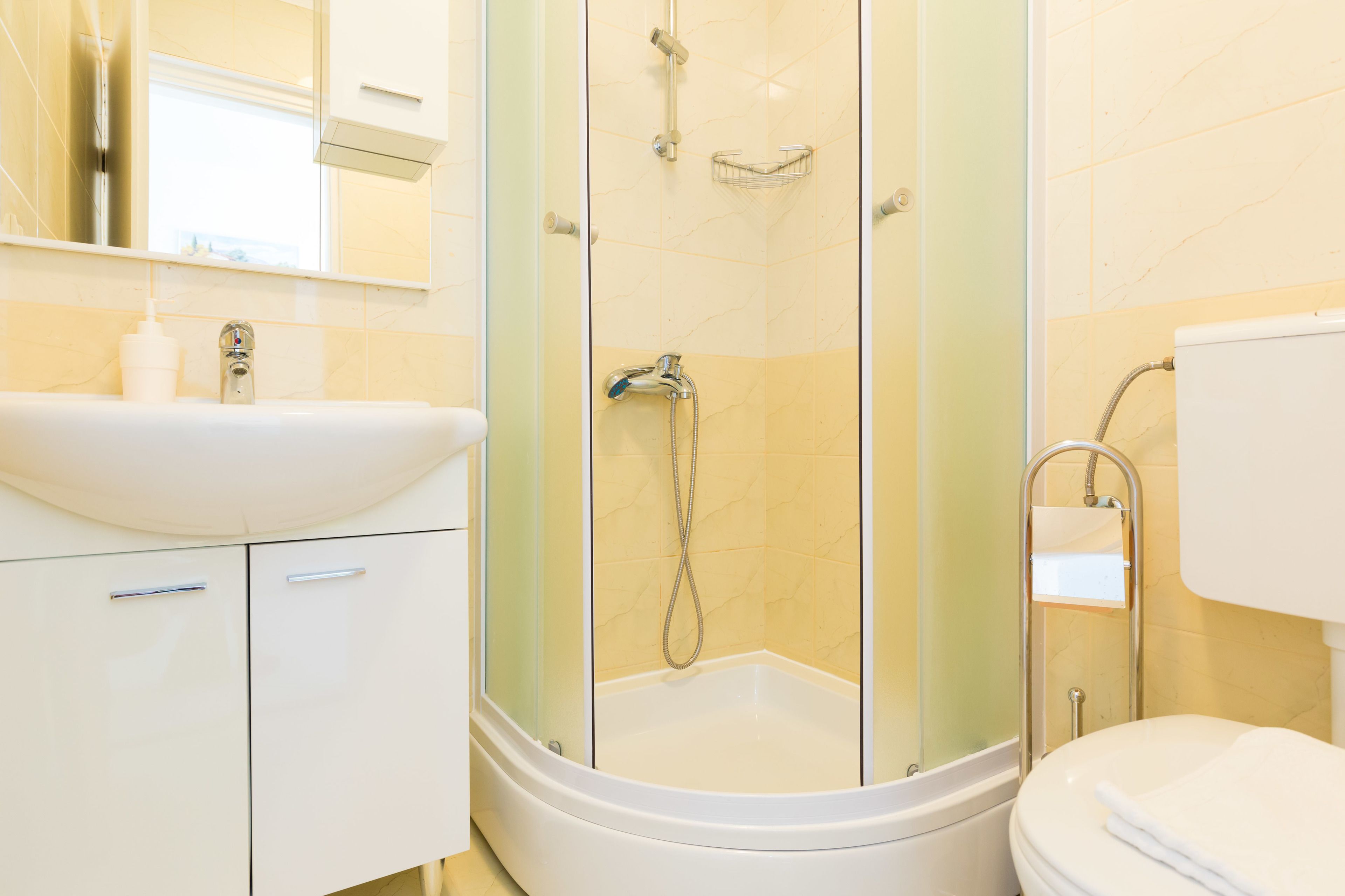 Ein modernes Badezimmer mit einer Duschkabine, einem weißen Waschbecken und einer Toilette.