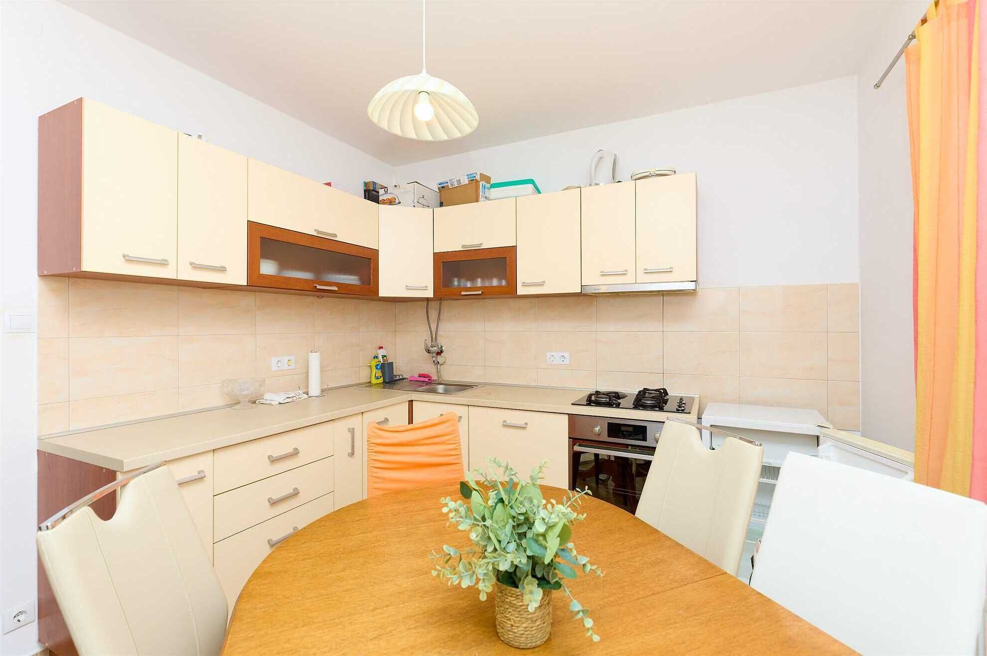 Una cocina compacta con armarios de colores claros, una mesa de comedor de madera y una lámpara colgante.