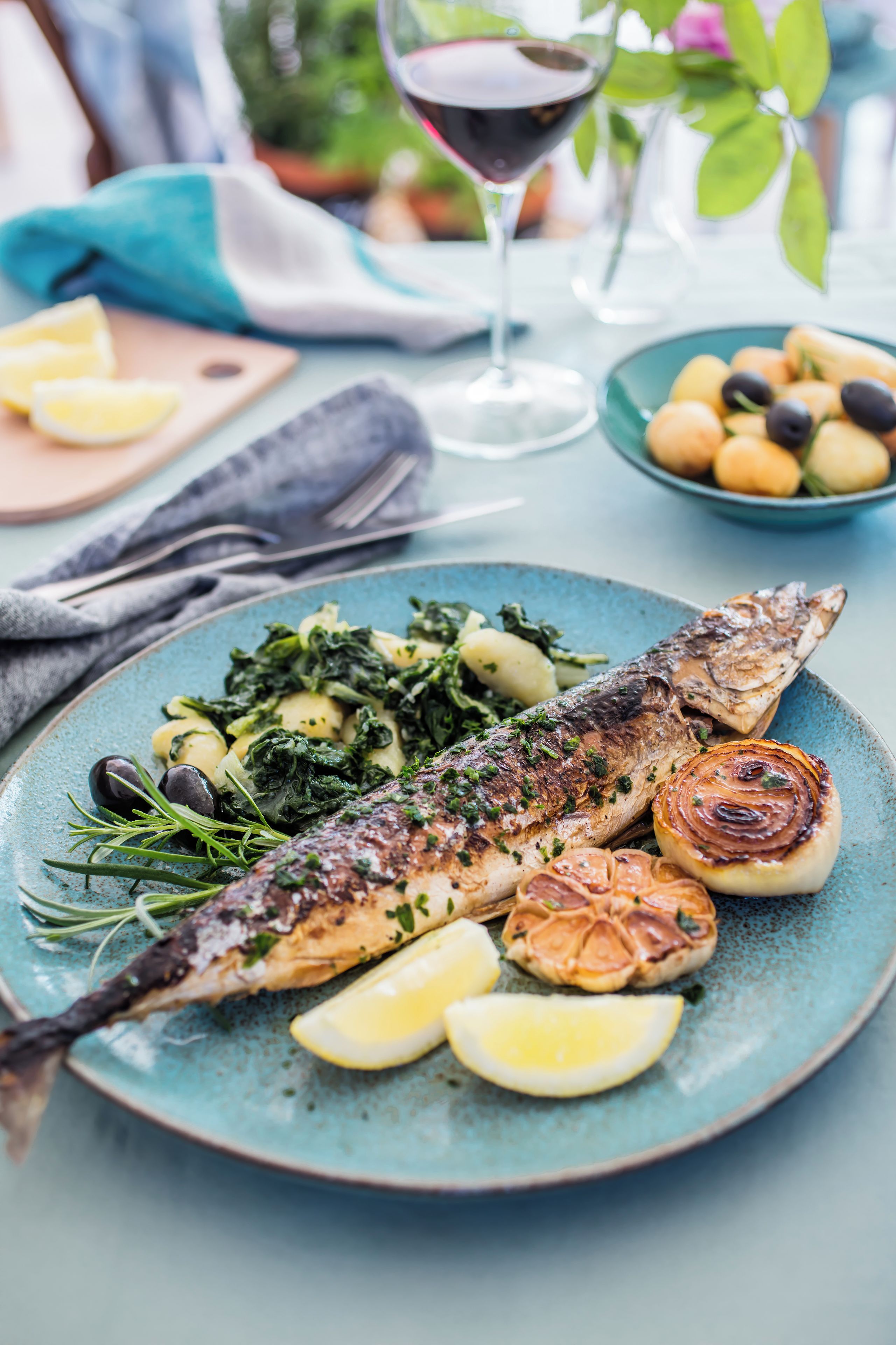 A plate of grilled fish with lemon slices and roasted potatoes.