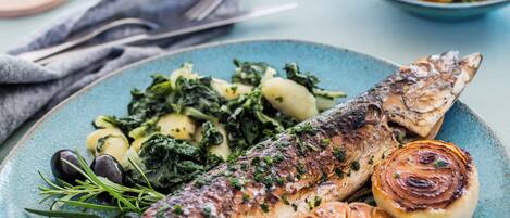 A plate of grilled fish with lemon slices and roasted potatoes.