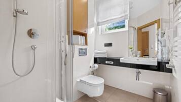 A modern bathroom with a glass-enclosed shower, a white toilet, a black countertop sink, and a mirror above the sink.