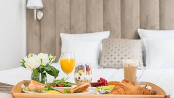 A breakfast tray with toast, fruit, yogurt, and a croissant on a wooden table.