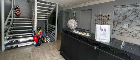 A modern interior with a staircase, a reception desk, and a wall-mounted key rack.