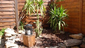 Jardí amb tanca de fusta, diferents plantes i una bassa per a ocells.