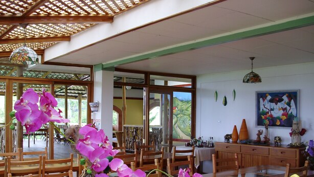 Un restaurante con muebles de madera, una planta de orquídea grande y un mural en la pared.