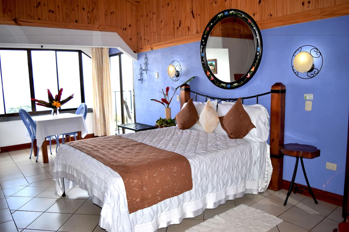 A bedroom with a large bed, a desk, and a chair.