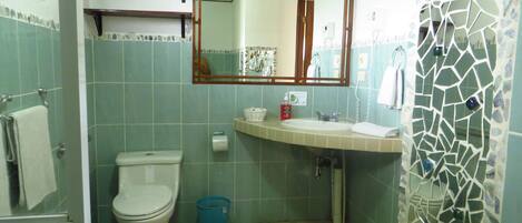 A bathroom with a toilet, sink, and mirror.